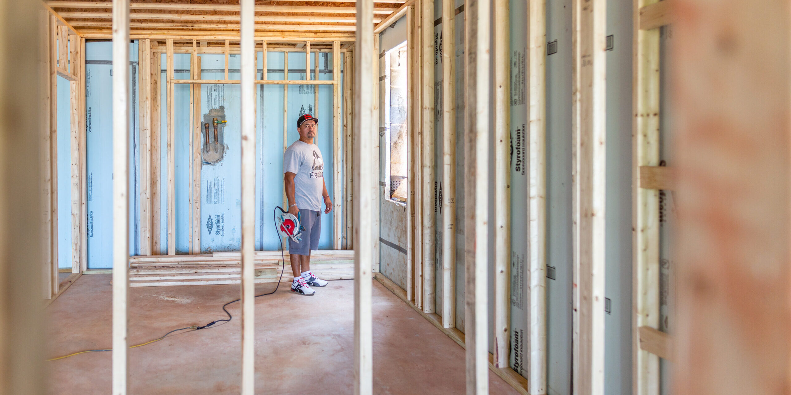 Latino contractor inspecting the wooden frame structure of a house under construction in a residential site during the framing stage