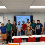 Participantes en una clase de HDS Biz Solutions sobre la licencia de contratista en Maryland, posando junto a la instructora frente a un aula, con una presentación en pantalla