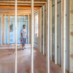 Latino contractor inspecting the wooden frame structure of a house under construction in a residential site during the framing stage