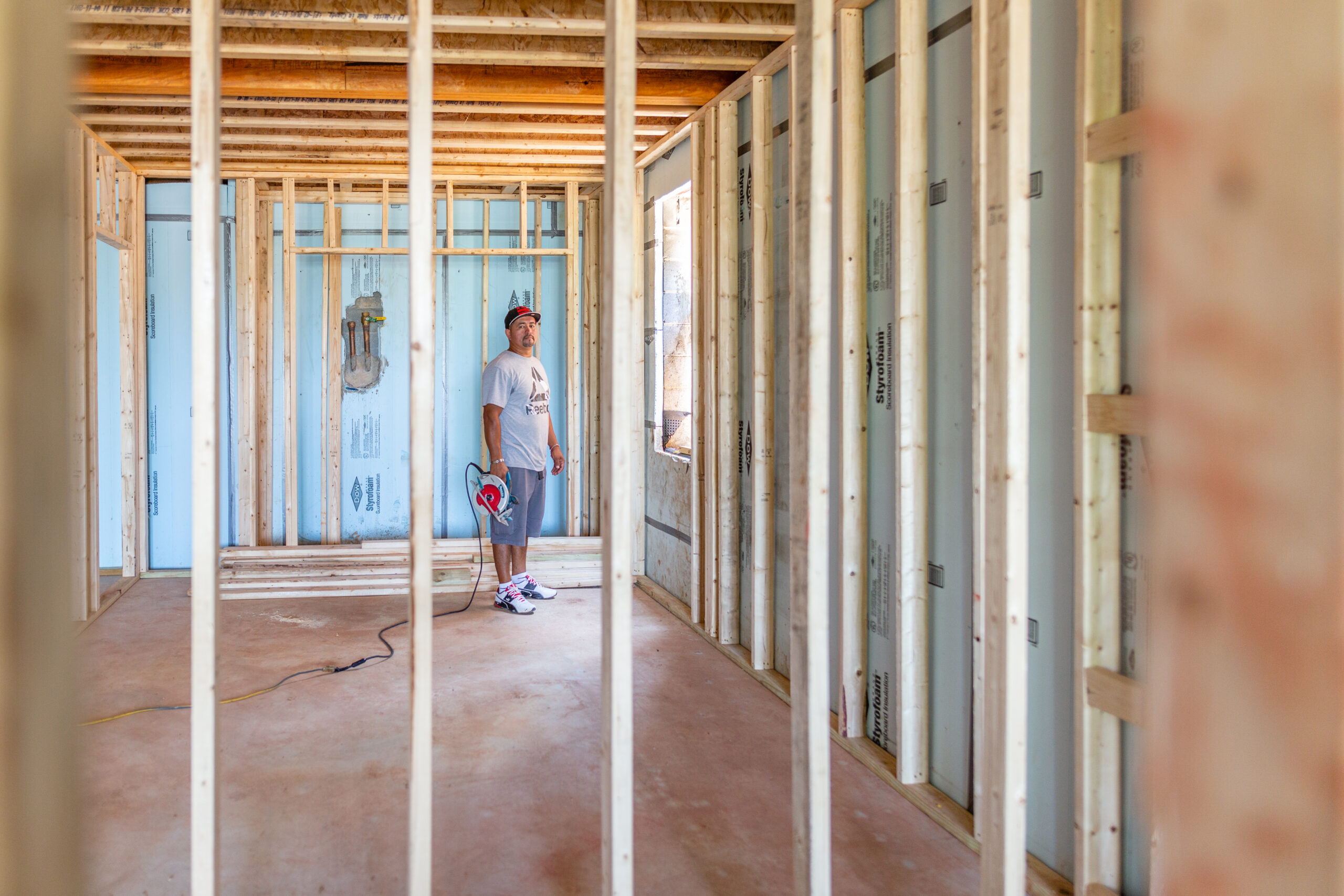 Latino contractor inspecting the wooden frame structure of a house under construction in a residential site during the framing stage