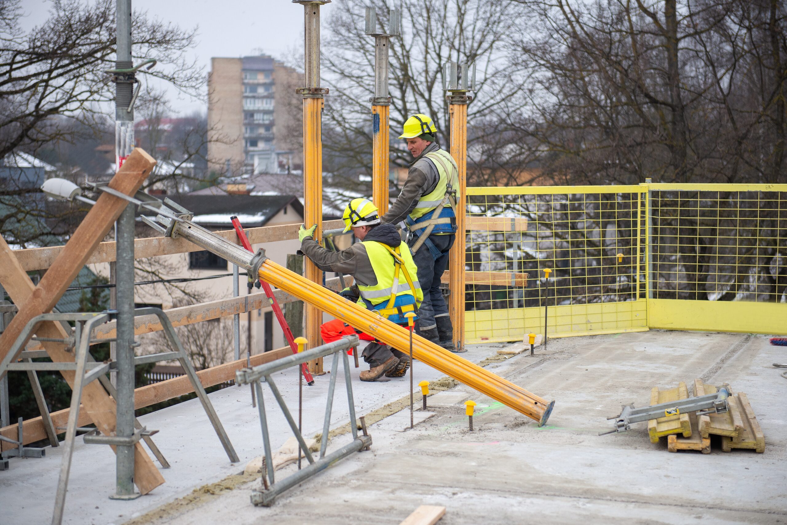 Dos trabajadores de la construcción en proceso de trabajo en el sitio de construcción con casco y chaleco de alta visibilidad