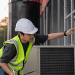 Hombre en casco de seguridad lubricando la tubería de agua para reducir la fricción y proporcionar una lubricación duradera. Hombre plomero en mono de trabajo instalando sistema de agua en el apartamento. Concepto de obras de fontanería